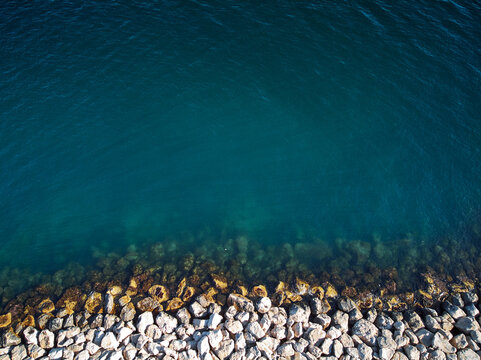 Aerial view of a rocky shoreline meeting clear blue ocean water.