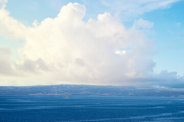 Bright Sky with Clouds Above a Calm Ocean Horizon..