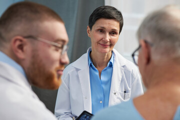 Doctors discussing patient care in modern medical office, focusing on healthcare solutions while utilizing technology for better diagnosis and treatment planning