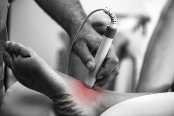 A physical therapist uses laser therapy on a patients ankle to reduce pain and promote healing. The...