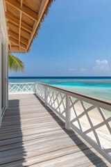 Fototapeta premium A wooden deck overlooking the ocean with a white railing. The railing is decorated with a pattern of white squares. The deck is empty and the ocean is calm