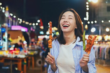 Happy young Asian woman walking in the night market,woman enjoying street food at local night market