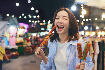 Happy young Asian woman walking in the night market,woman enjoying street food at local night market