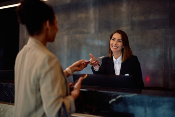 Happy concierge talking to guest who is checking in at hotel.
