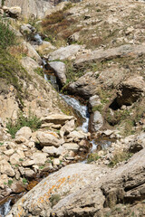 Kabardino-Balkaria. Chegemsky Reserve. Autumn 2024. Stormy and foaming transparent waters of mountain river Abai-Su flow in thin streams between stones and boulders created by nature.