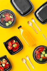 Healthy takeaway food in disposable delivery boxes and orange juice in a bottle, top view