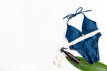 Summer beach tropical flat lay with bikini swimsuit and green leaves, top view