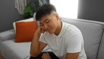 Fototapeta premium Handsome young asian man smiling in a modern living room with a cozy interior and stylish decor