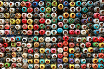 Colorful spray cans lined in a box and made a abstract pattern.