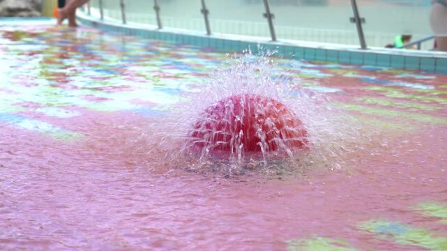 Pink water nozzle in a pool at a waterpark during the day, medium shot