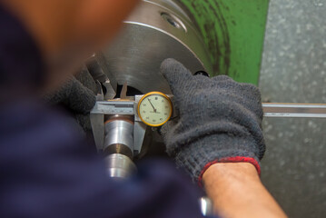 Close up scene the machine operator measuring diameter of turning parts by dial Vernier caliper.