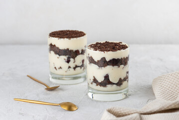 Cherry, vegan cream with shea butter and chocolate biscuit layered dessert in glass on a light table. Black forest trifle.