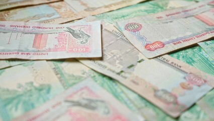 Scattered united arab emirates dirhams banknotes depict currency scenes from uae.