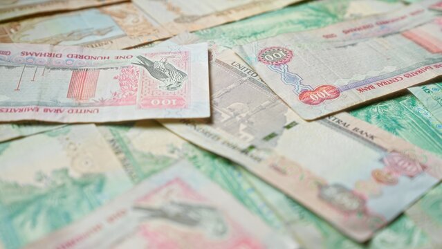 Scattered united arab emirates dirhams banknotes depict currency scenes from uae.