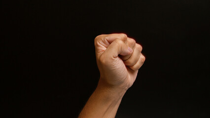 Clenched fist of a man against a dark background shows strength, determination, and power.