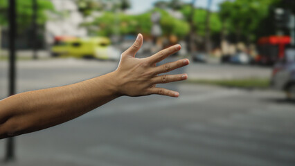 Man's hand with five fingers extended gestures on a busy city street, emphasizing urban life and...