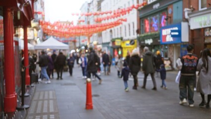 Obraz premium Busy street scene in london's chinatown capturing blurred winter crowds, festive lanterns, and diverse people bustling amid iconic uk architecture.