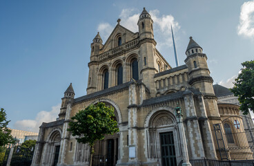 St. Anne Cathedral, in Belfast, Northern Ireland. It features a grand arched entrance, detailed stone carvings, and large windows