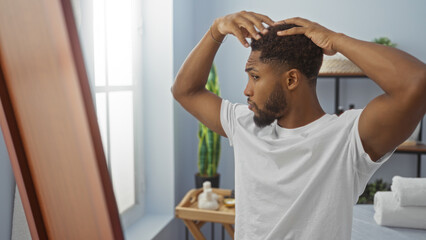 Handsome man grooming in spa room, adjusting hair in front of mirror, reflecting self-care and wellness in stylish beauty salon