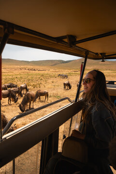 Young woman enjoying a safari trip, observing wildebeest grazing in the picturesque landscape of ngorongoro crater, tanzania