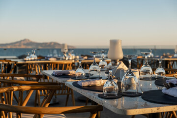 Fototapeta premium Perfectly arranged restaurant tables by the ocean, with fine glassware