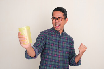 A man clenched fist showing excited expression while looking at drink tumbler that he hold