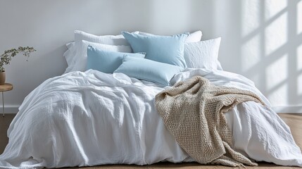 A tranquil bed with crisp white bedding, light blue pillows, and a soft woven throw in matching tones for a