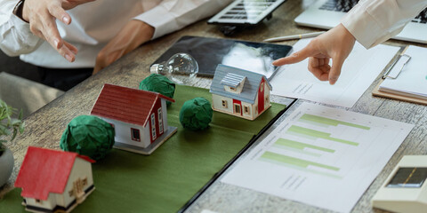 Sustainable Development and Housing Models. Professionals discussing sustainable home designs with...