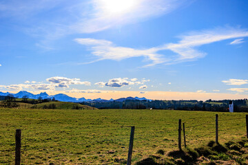 Obraz premium Alpine landscape with green meadows, snow-capped mountains and Saharan dust glow at sunset, Bavaria, Germany, 21.3.2025