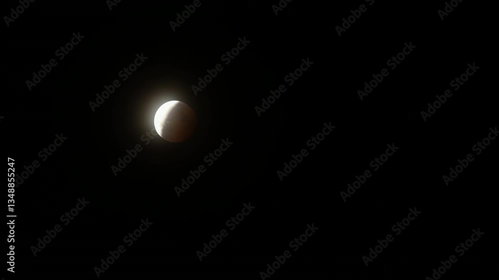 Poster wide timelapse of the end of the total lunar eclipse on march 14th, 2025, with hazy clouds passing