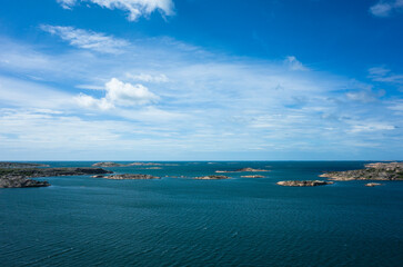 A breathtaking view of the Swedish west coast near Hunnebostrand, featuring a vast blue sea dotted with small islands and a serene horizon under a clear sky