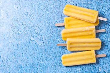 Yellow popsicles on blue background. Top view. Copy space