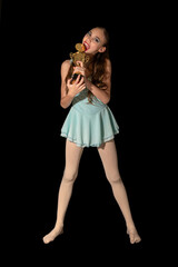 Funny Young Ballerina Celebrates First Place Victory with Golden Trophy. A 12-year-old girl isolated on a black background