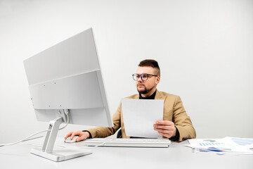 A businessman at a computer in an office, analyzing stock market and inflation charts, sorting through papers. The concept is to capture the tense decision-making process in times of economic instabil