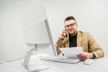 A businessman at a computer in an office, analyzing stock market and inflation charts, sorting through papers. The concept is to capture the tense decision-making process in times of economic instabil
