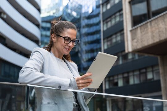Portrait of a successful business woman using digital tablet in front of modern business building. Businessperson office worker design professional occupation, innovative work outside of workspace.