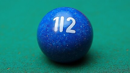 Close-up of a blue billiard ball with the number 112 on a green table.