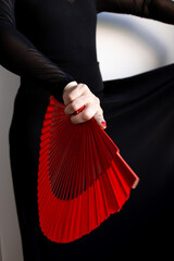 Elegant female holding red fan in black attire