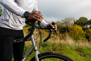 Cyclist holding handlebars of gravel bike wearing smartwatch