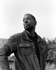 Pensive black man looking away in black and white portrait
