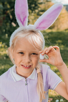 Child with bunny ears enjoying an Easter egg hunt outdoors