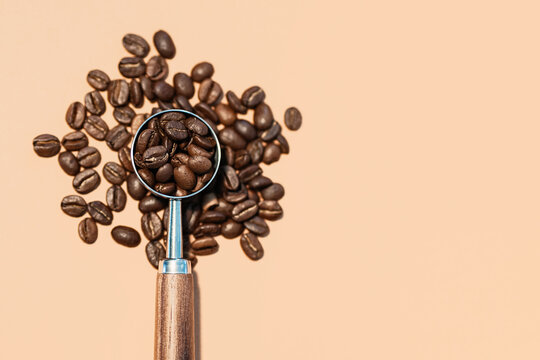 Coffee beans with metal scoop on beige background