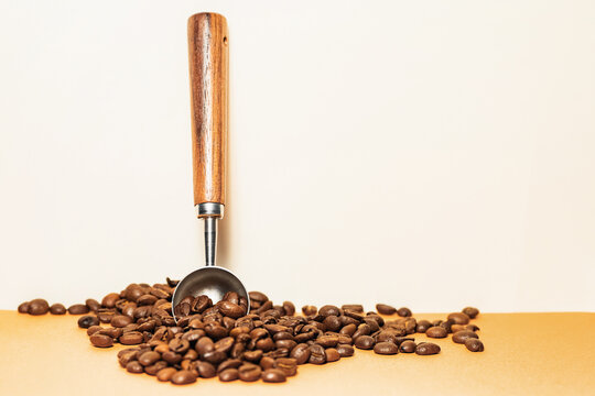 Coffee beans with metal scoop and wooden handle close up