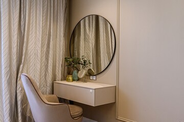 chic vanity area with a round mirror, floating shelf, decorative objects, and a stylish chair. A...