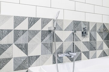 Modern bathroom featuring triangular patterned tiles in shades of gray and white, complemented by...