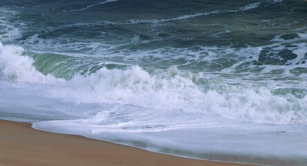 Ocean shore close-up. Wet sand. Sea foam. Waves. Color image. Poster. Wallpaper. Background. Postcard.