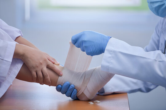Close-up side view of a Doctor in a hospital bandaging a patient's ankle and foot