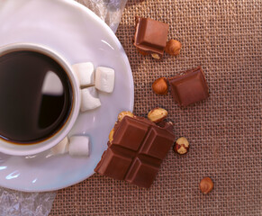 Close-up of coffee, chocolate with hazelnuts, and marshmallows on burlap