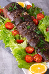 Baked catfish clarias with incisions on the surface, seasoned with salt and spices, stuffed with onion rings. Served with a salad of fresh vegetables and lemon wedges