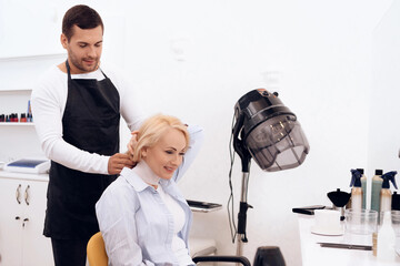 Stylist dresses hairdressing collar on mature woman's neck. Female haircut.